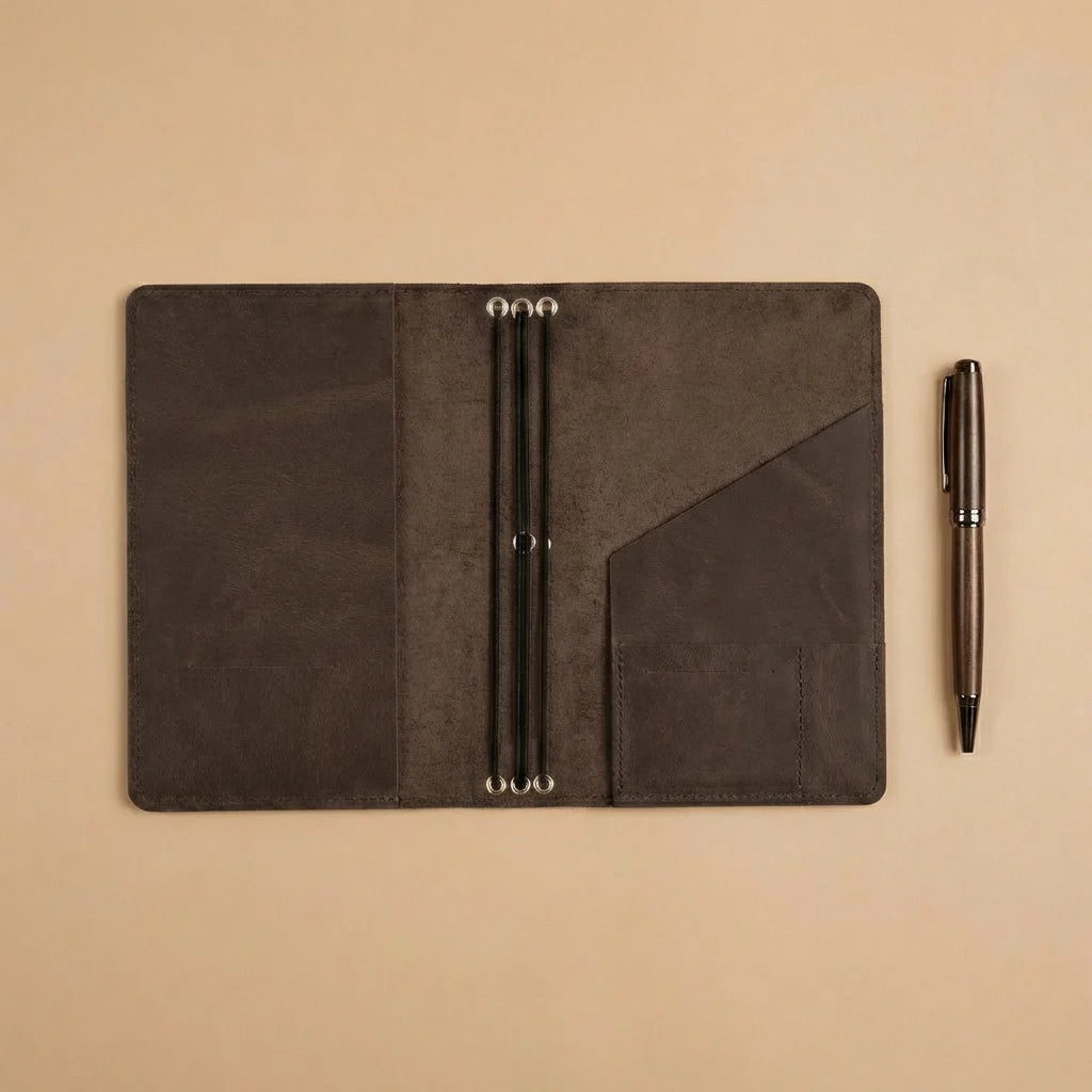 Dark brown leather notebook with pen on a beige background