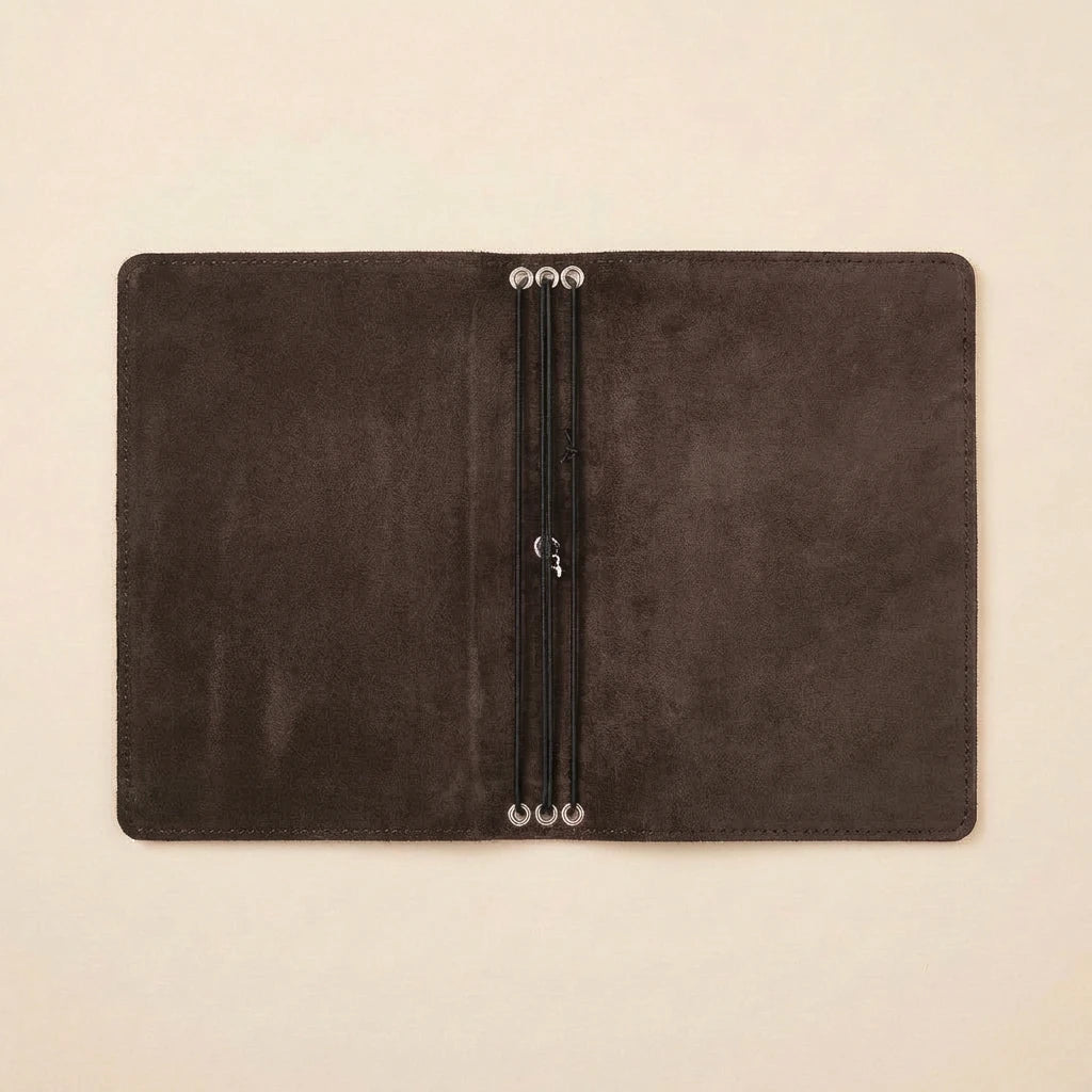 Dark brown leather notebook with a pen holder on a beige background