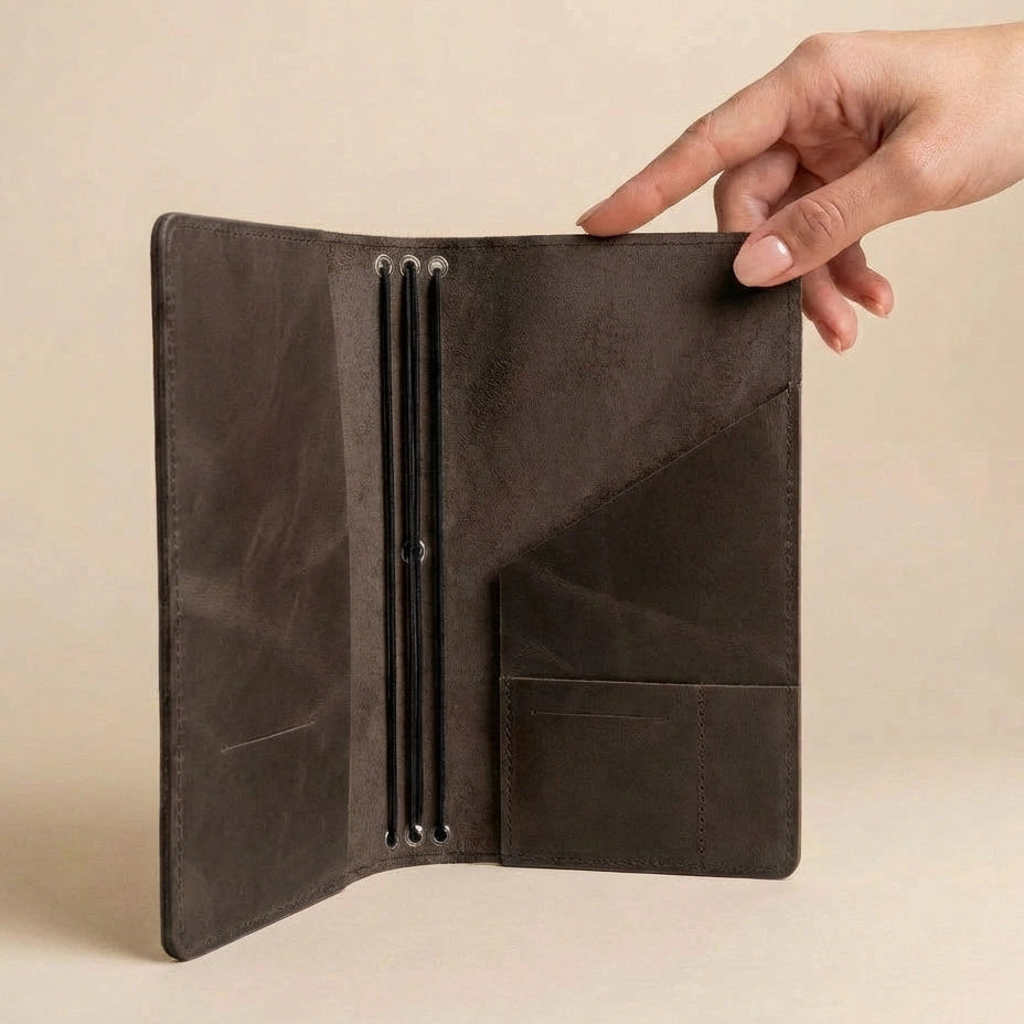 Brown leather wallet held open by a hand on a beige background