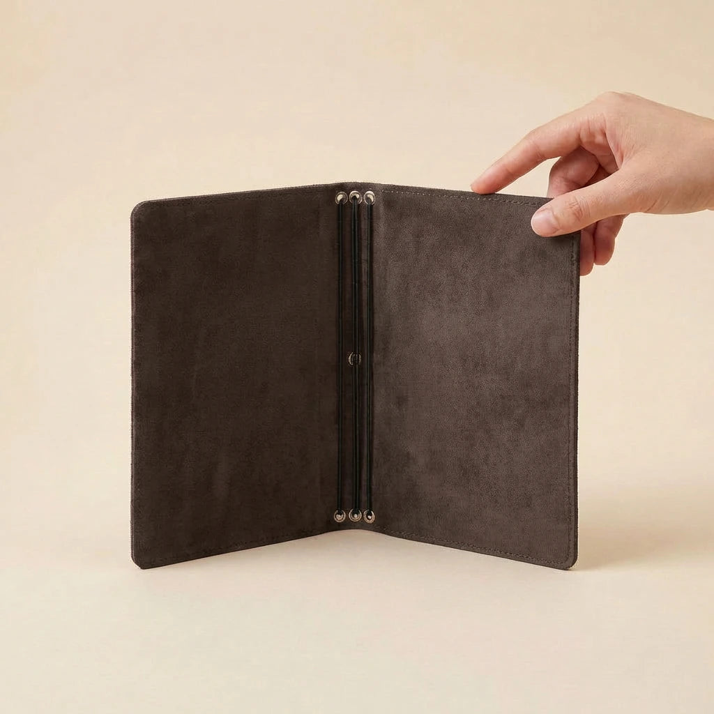 Open brown leather journal cover held by a hand on a beige background