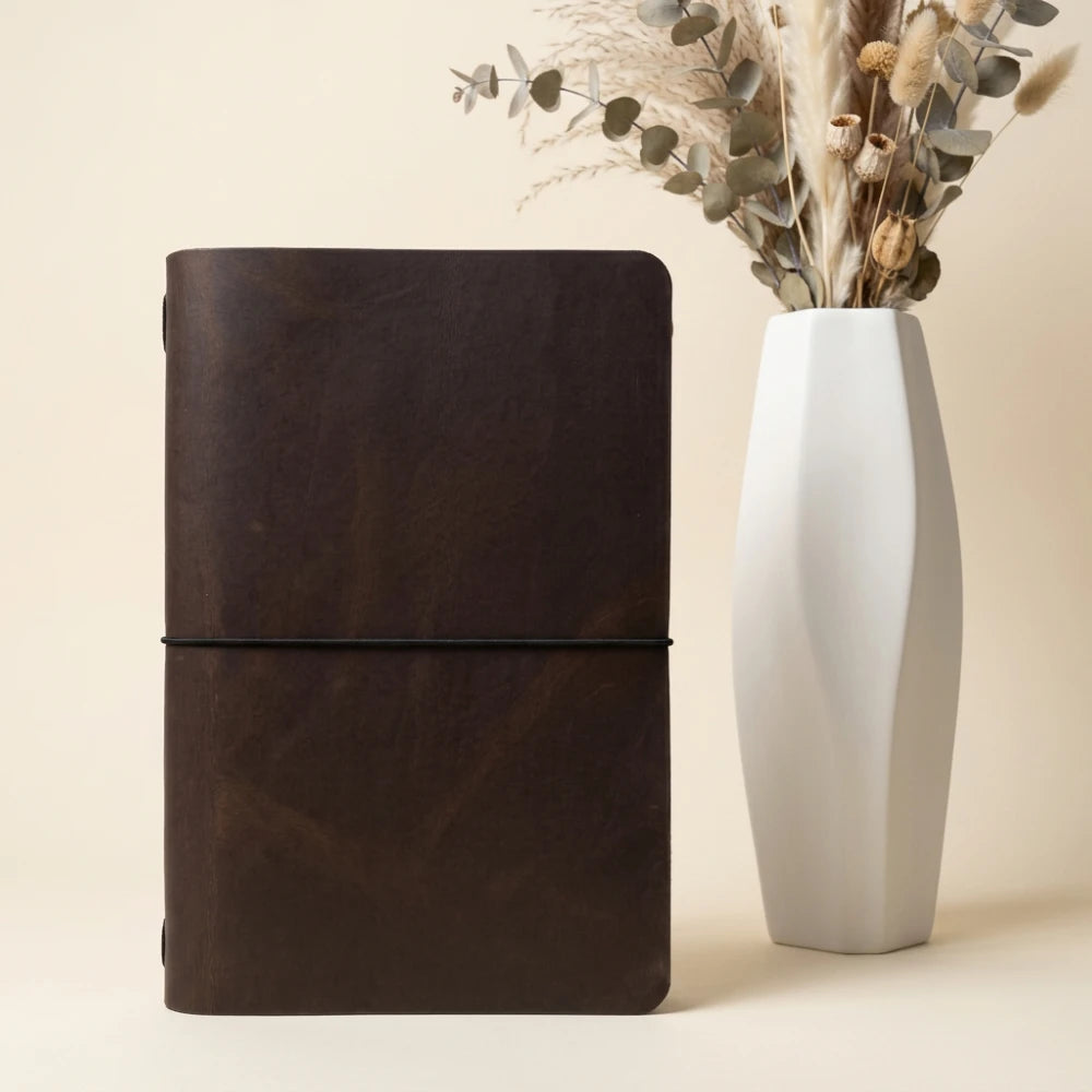 Journal holder revealing soft leather lining and a single elastic retention strap.