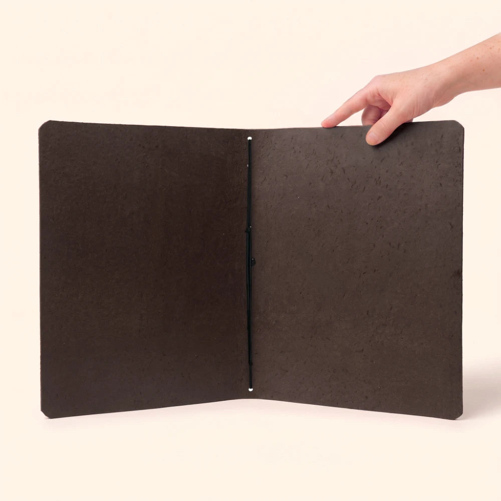 Natural leather journal sleeve with plain pages and a minimalist handcrafted structure.