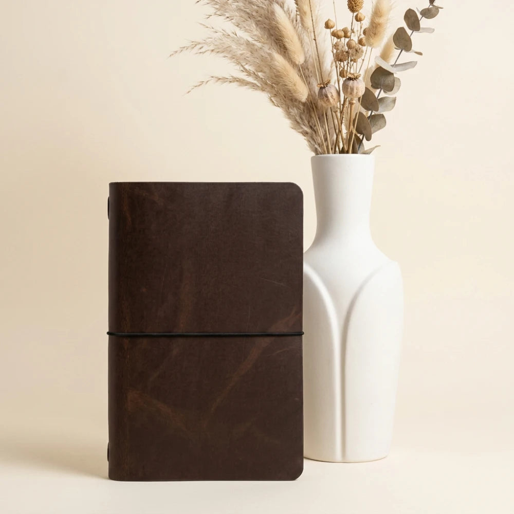 Leather notebook sleeve displayed with blank pages and flexible interior elastic support.