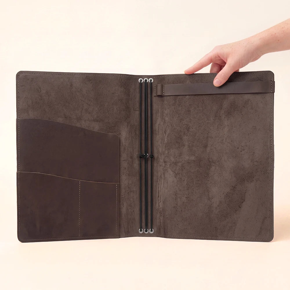 Genuine leather journal case featuring a structured interior with pockets and elastic cords.