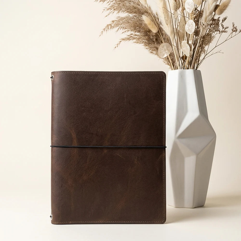 Open handmade leather journal displaying a functional pocket and elastic cord arrangement.