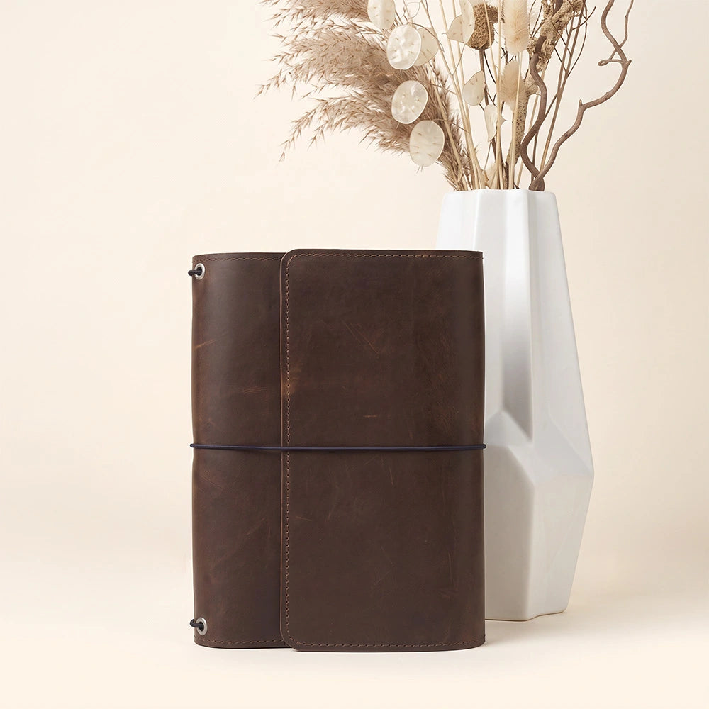 Genuine leather notebook organizer offering interior storage and secure writing instrument loop.