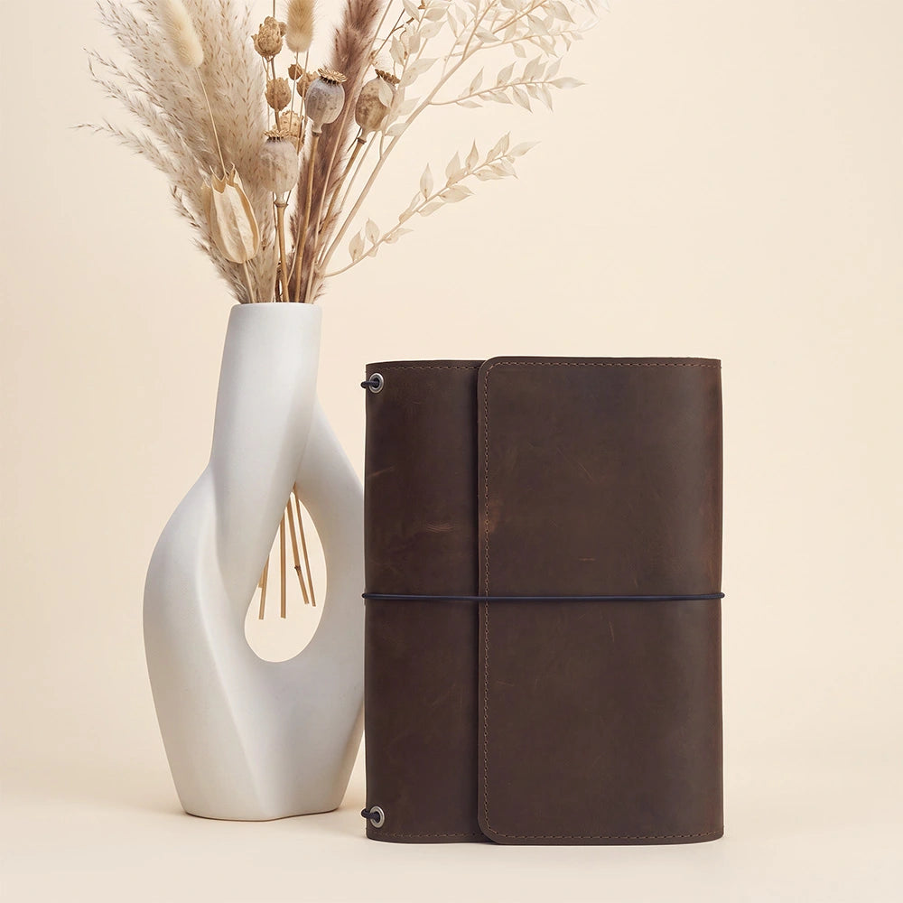 Leather notebook protector with spacious inside compartments and integrated pen carrying strap.