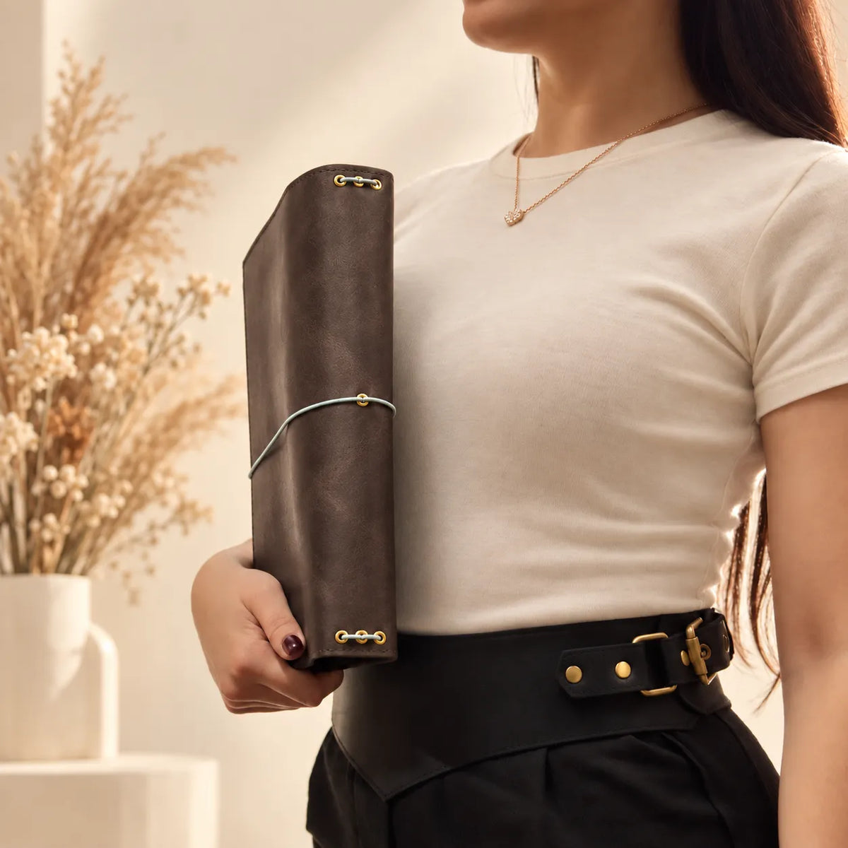 Female hands showcasing a natural leather notebook cover with a timeless handcrafted design.