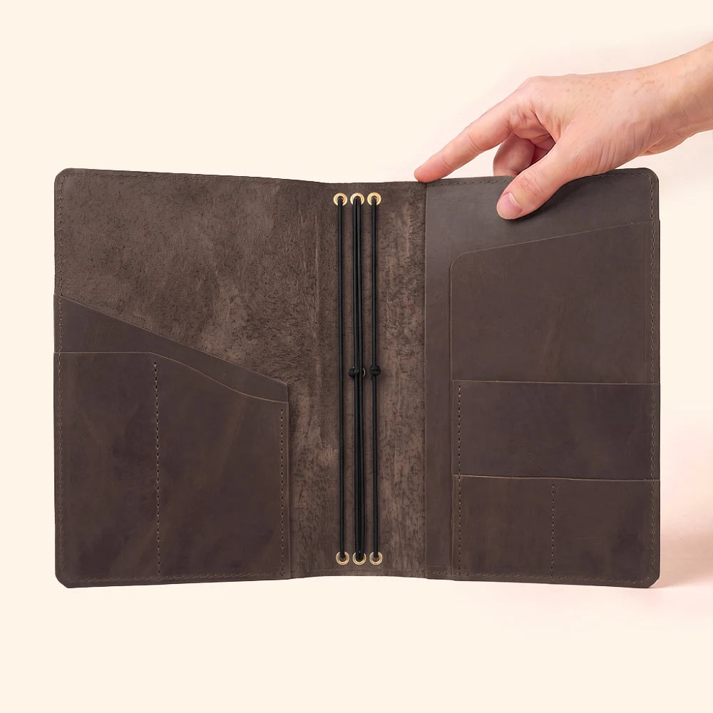 Handmade leather planner cover designed to securely hold three notebook refills.