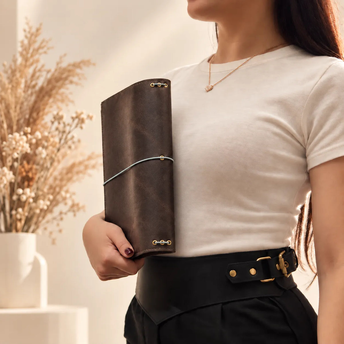 Female model presenting a leather notebook cover and highlighting its authentic natural leather finish.