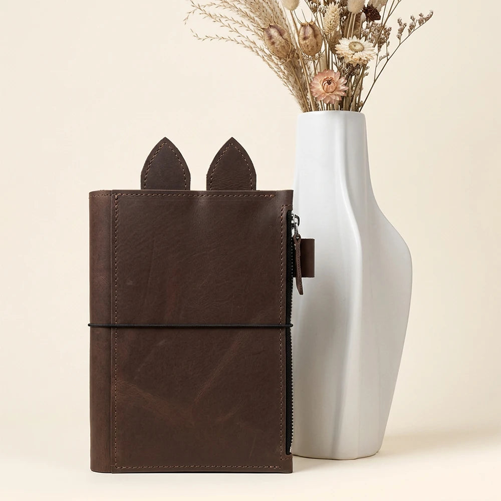 Handcrafted planner cover with decorative leather tabs and flexible elastic retention straps.