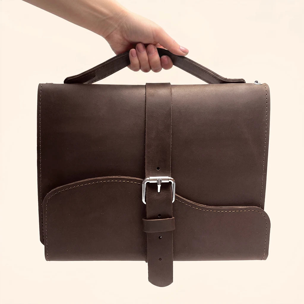 Refillable notebook cover crafted from genuine leather with three elastic bands and handle.