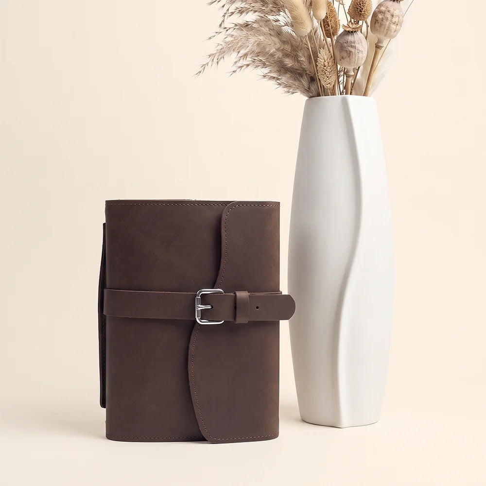 Leather journal holder with neatly arranged pockets, elastic pen keeper, built-in ribbon marker, and carrying grip.