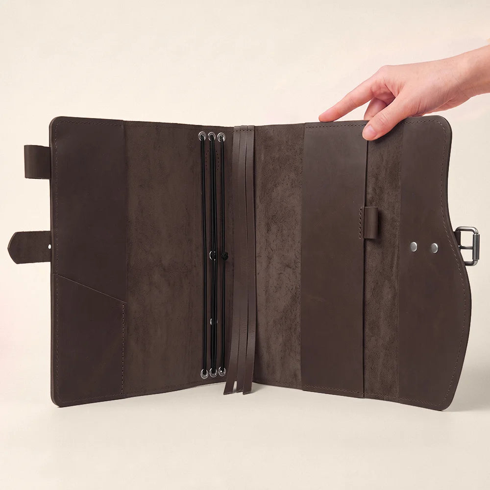 Natural leather journal carrier showcasing inner pockets, secure pen loop, integrated marker, and exterior handle.