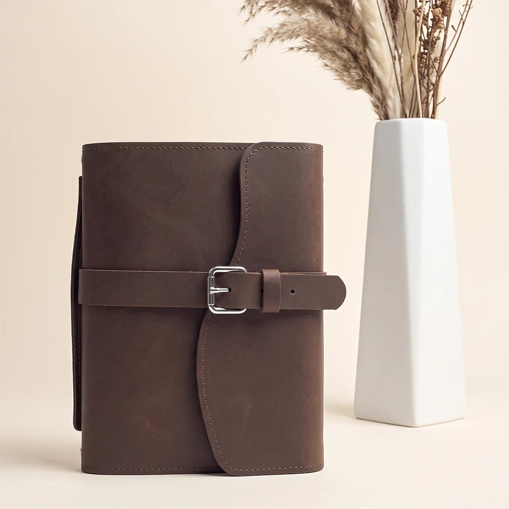 Leather notebook cover displaying spacious interior pockets, pen loop, integrated bookmark, and comfortable carrying handle.