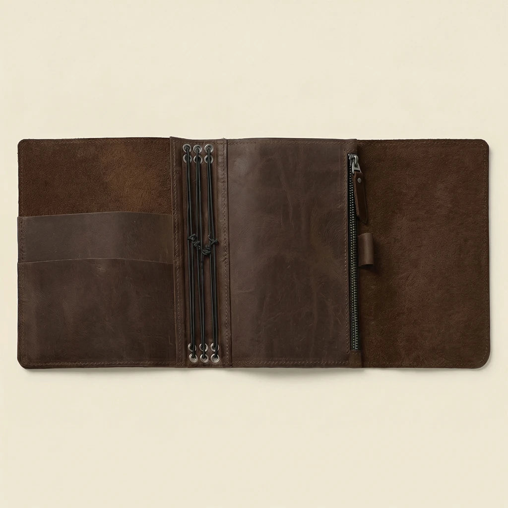 Brown leather journal with zippers on a beige background
