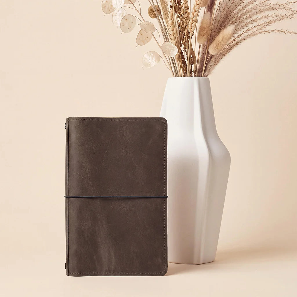 Refillable leather journal organizer featuring secure elastic loops and convenient storage compartments.