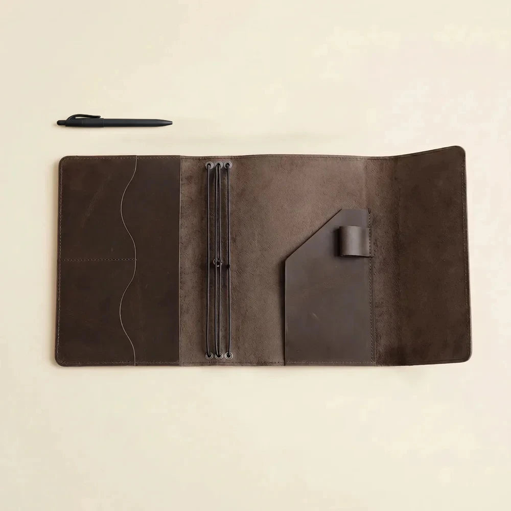 Brown leather refillable notebook cover featuring three elastic bands and inside utility pockets.