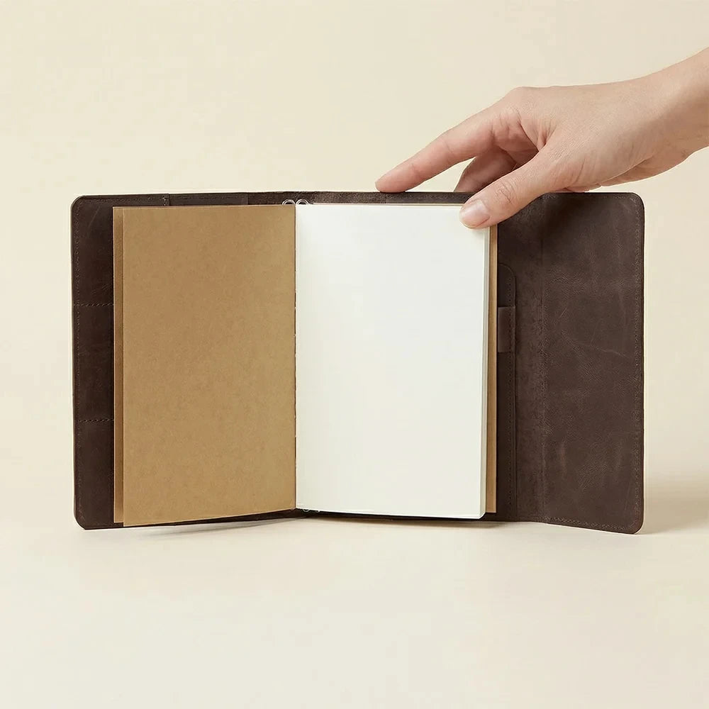 Genuine brown leather traveler's notebook cover with three elastics and inner card pockets.