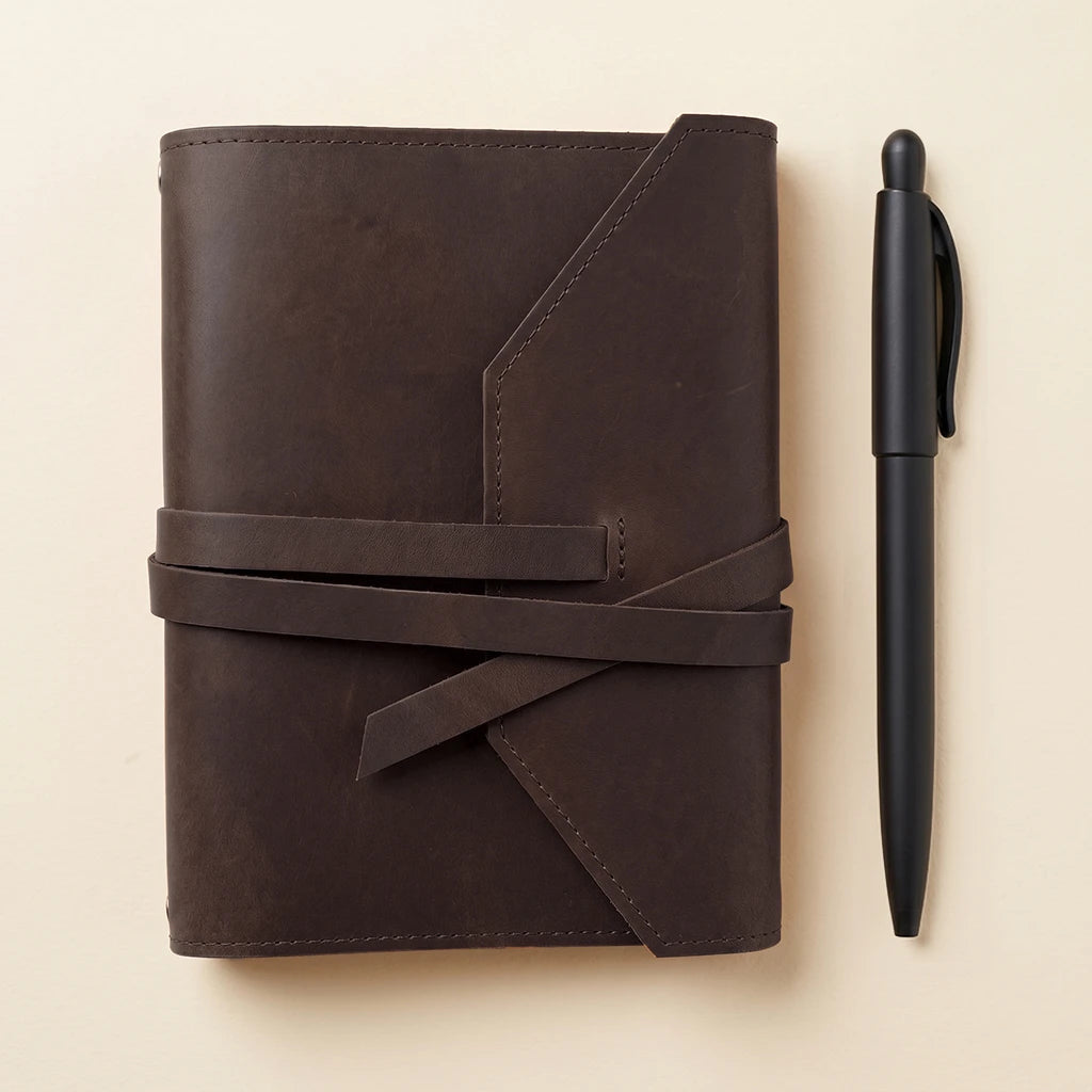 Durable leather notebook cover with flexible elastic closure and pen holder.