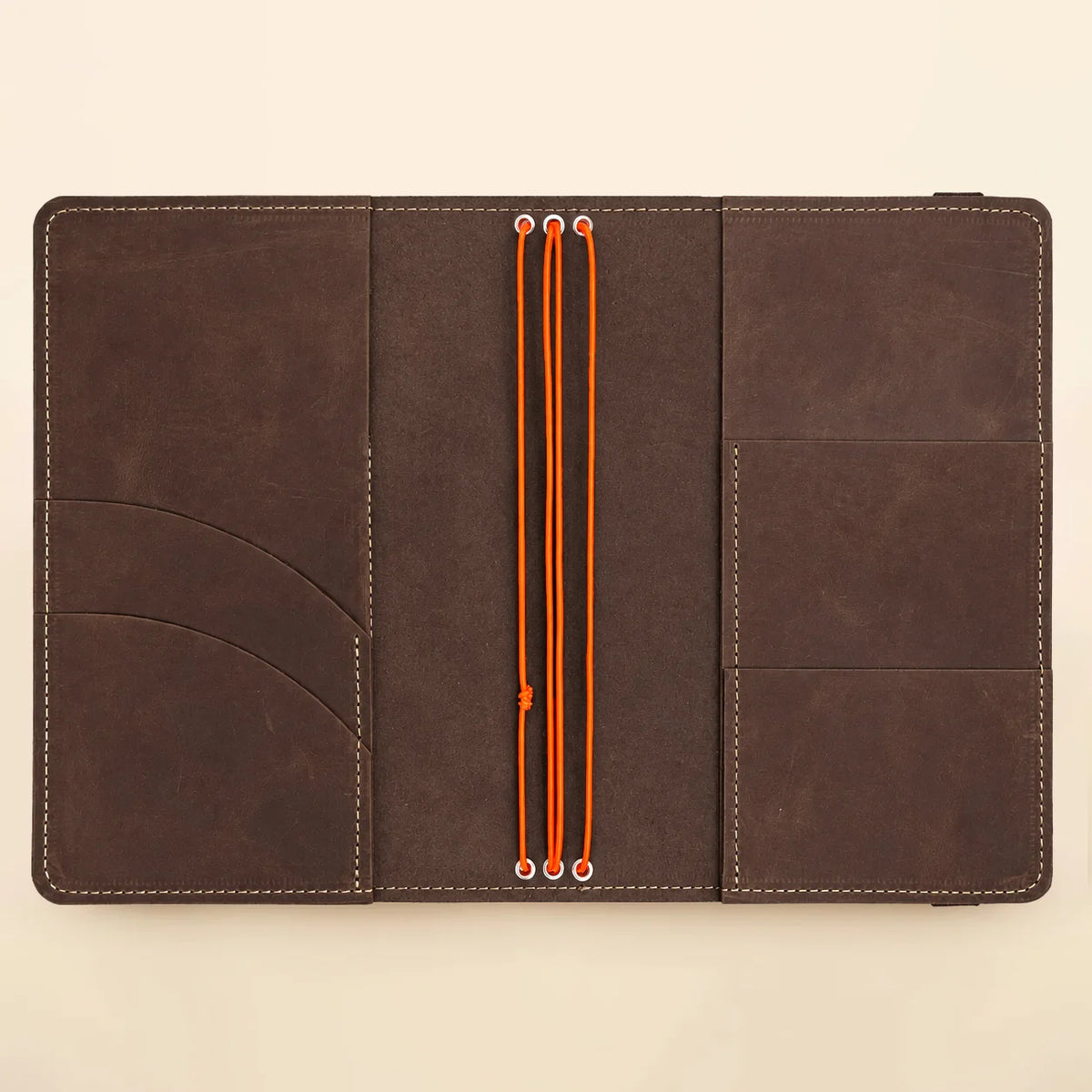 Natural leather notebook cover displaying three elastic bands and neatly arranged interior pockets.