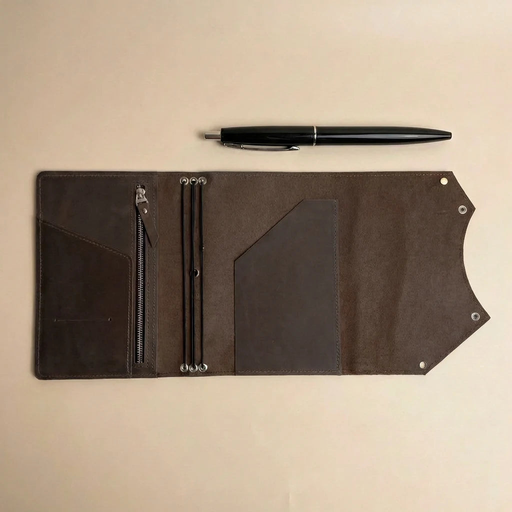 Brown leather journal cover with zipper pocket and pen on a beige background