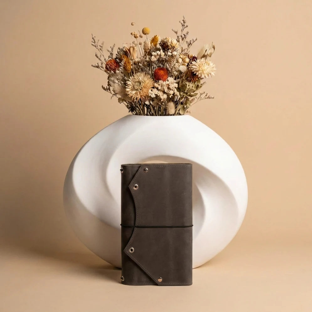 White spherical vase with dried flowers on a beige background