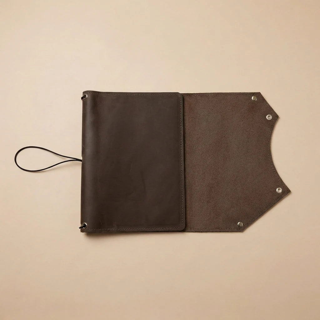 Brown leather journal cover with flap on a beige background