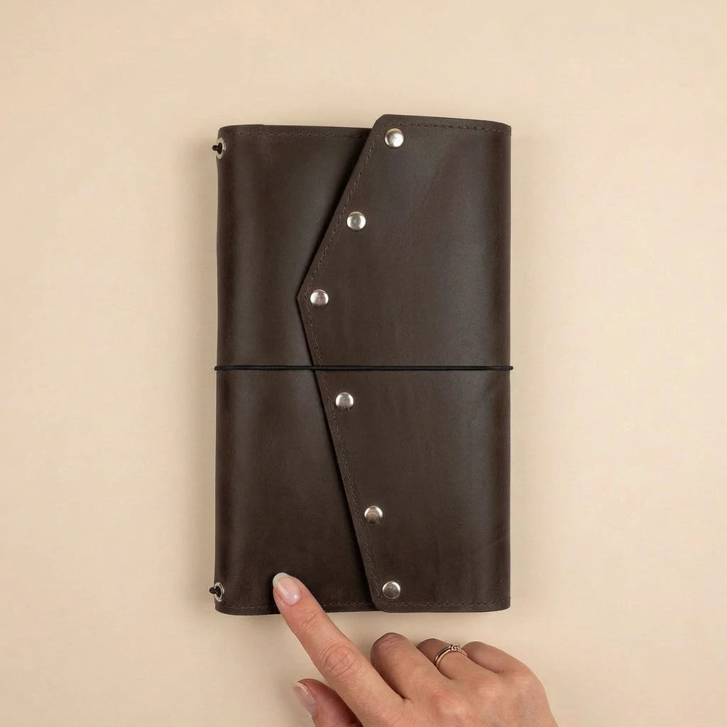 Brown leather journal with silver rivets on a beige background