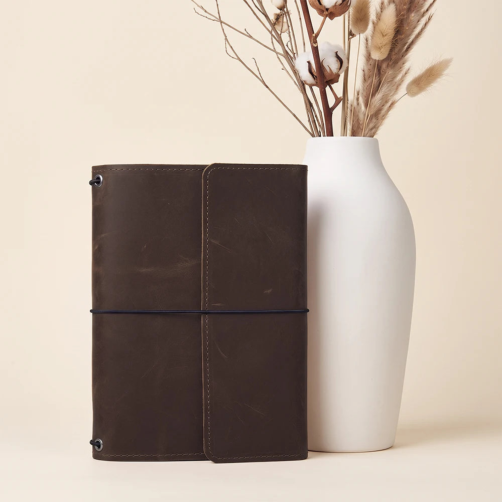Handmade leather journal holder with organized interior features for notebooks and small accessories.