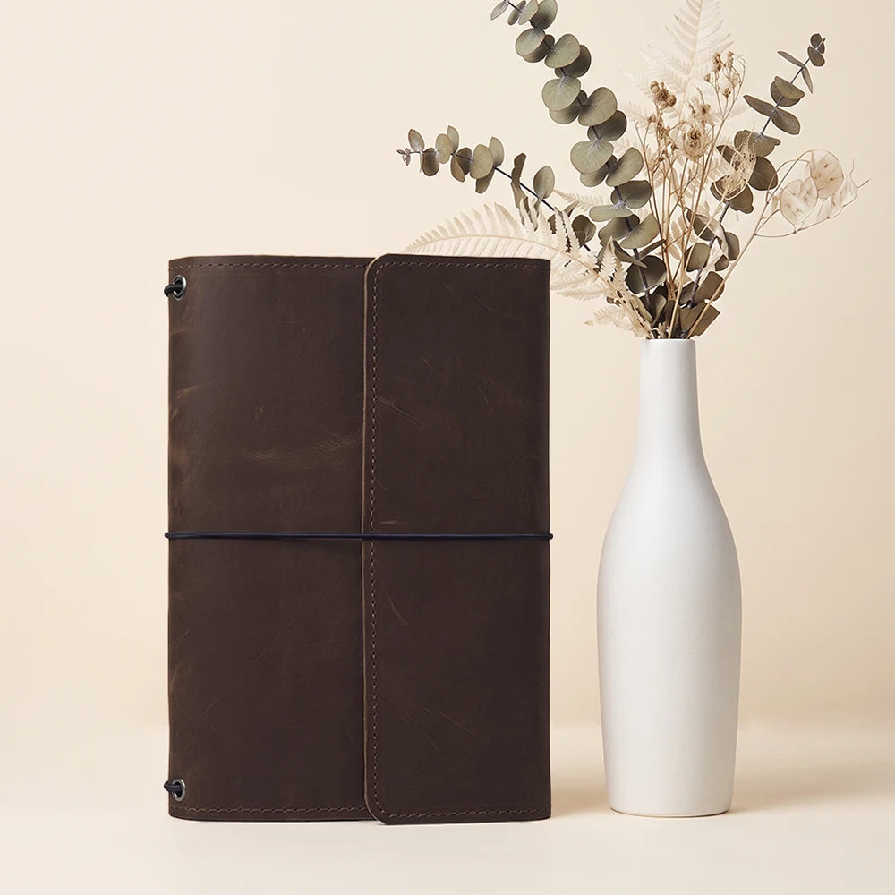 Refillable notebook cover crafted from genuine leather with organized storage and pen sleeve.