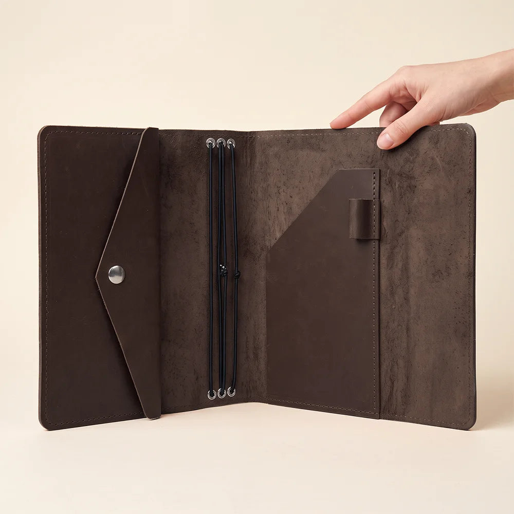 Leather notebook holder with flexible elastic bands and convenient interior storage compartments.