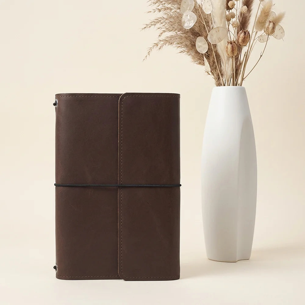 Natural hide notebook sleeve featuring organized storage areas and dedicated space for writing instruments.