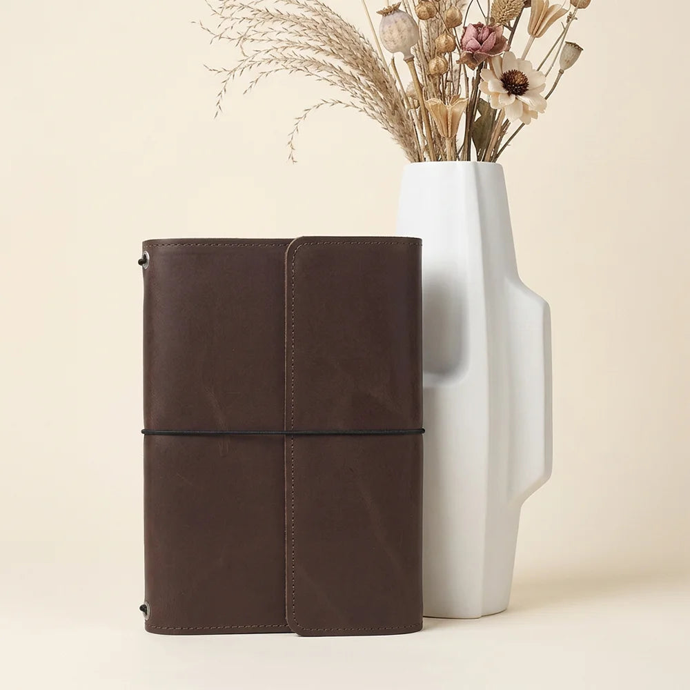 Handmade leather notebook case with organized interior pockets and an elastic pen holder