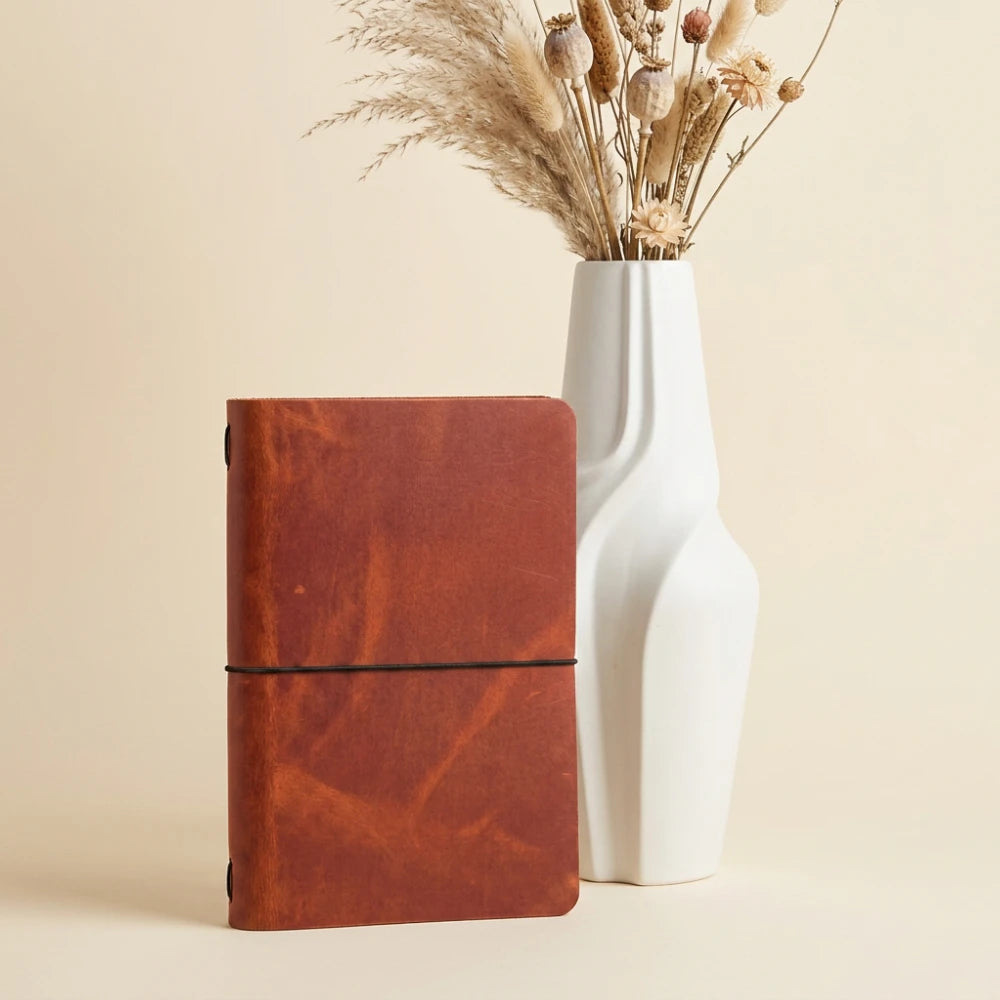 Brown leather journal sleeve with minimalist construction and neatly fitted notebook pages inside.