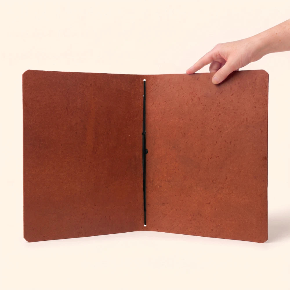Genuine leather notebook sleeve with handcrafted construction and flexible elastic retention inside.