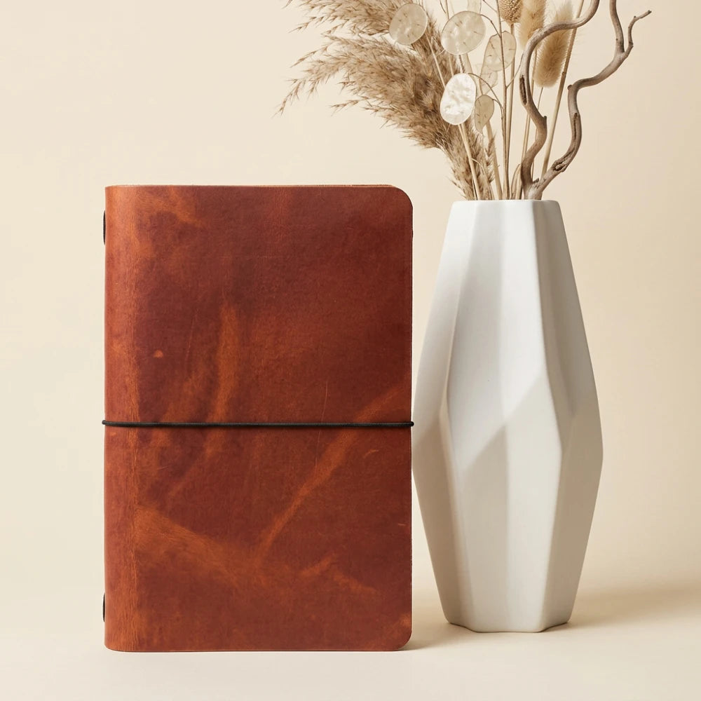 Handmade leather writing accessory with one elastic loop and a plain notebook.