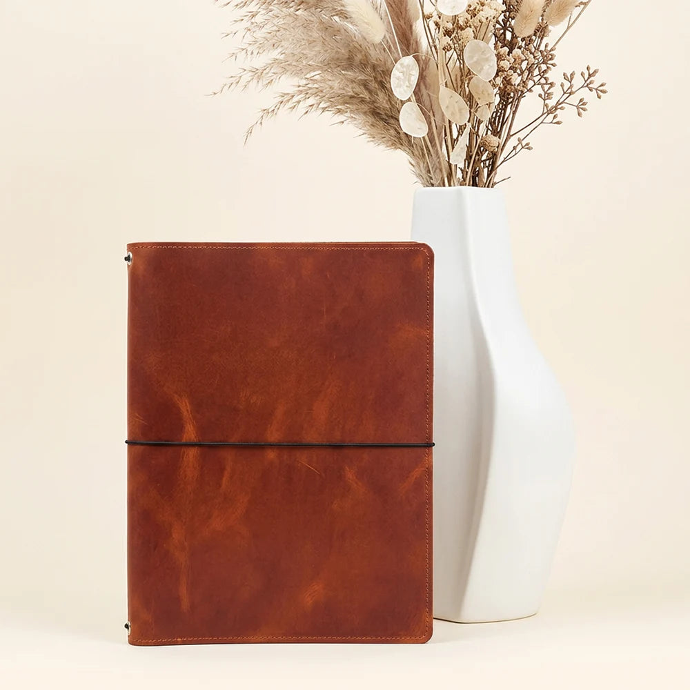 Reusable leather notebook cover featuring three elastic bands and organized interior pockets.