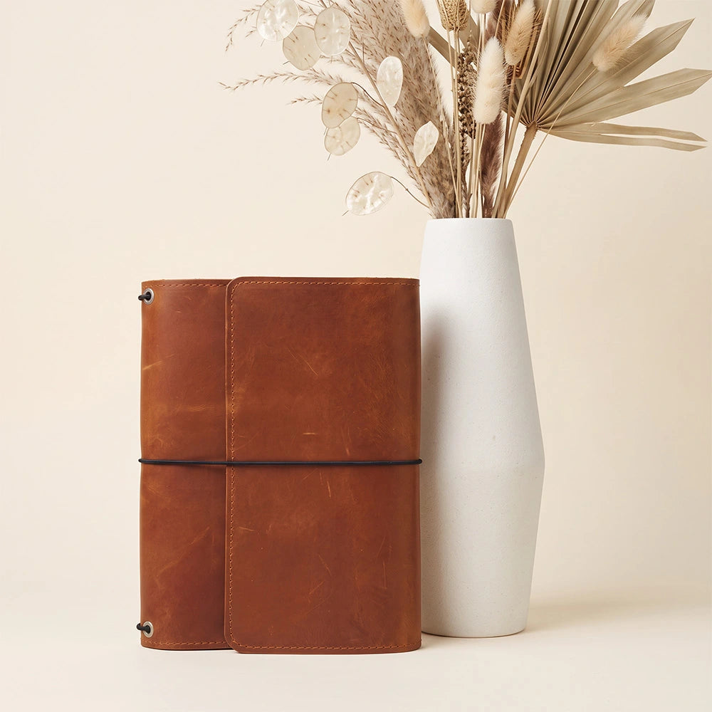 Leather notebook jacket offering interior organization and practical leather writing accessory holder.