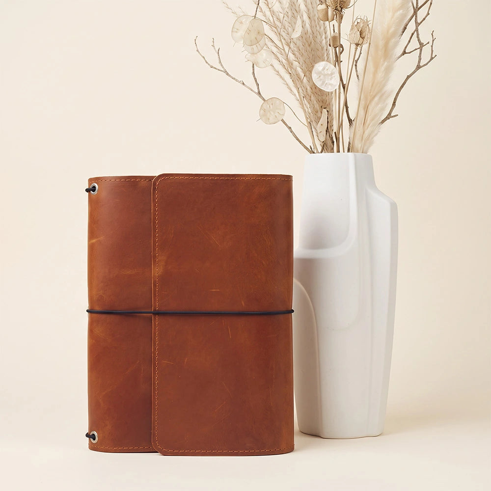 Refillable leather planner cover featuring interior card slots and stitched pen holder loop.