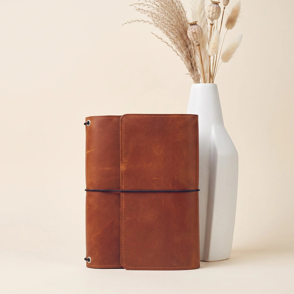 Handmade leather journal cover featuring card pockets and secure pen holder for organization.