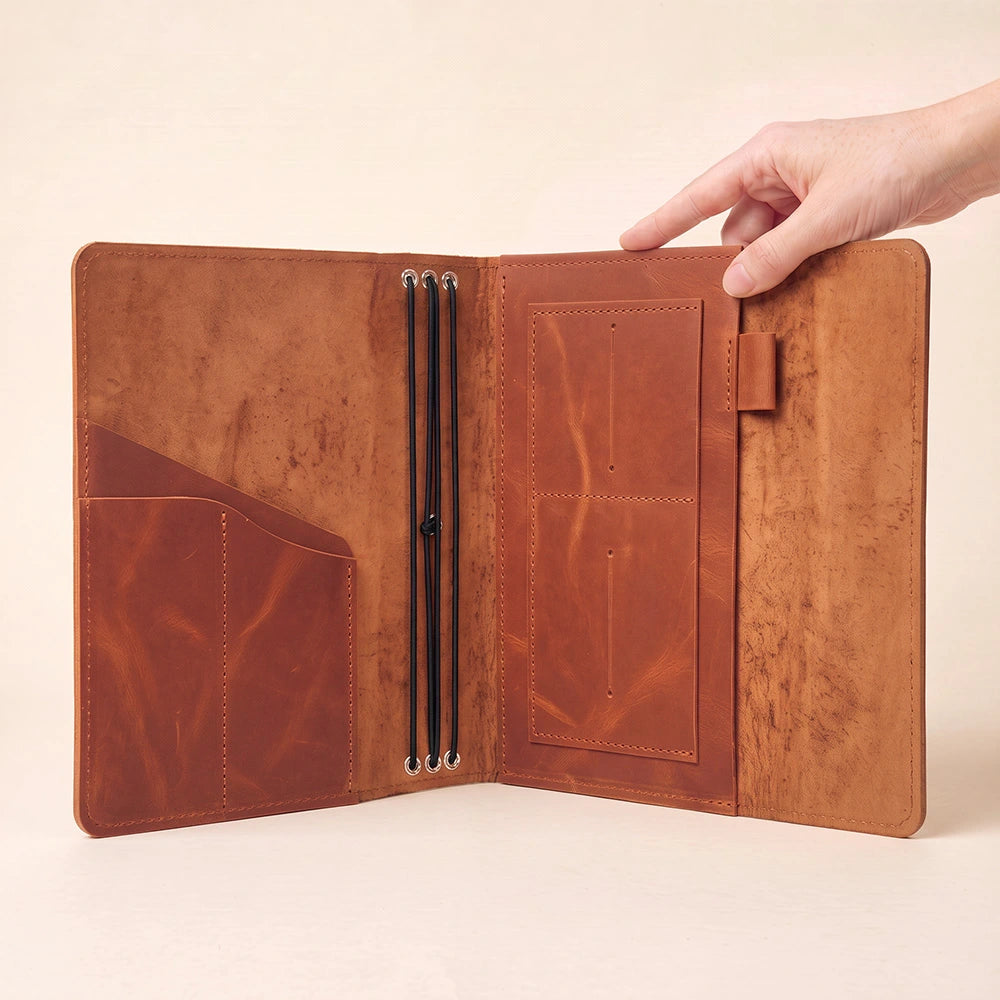Handcrafted leather diary holder featuring storage compartments and durable pen securing strap.