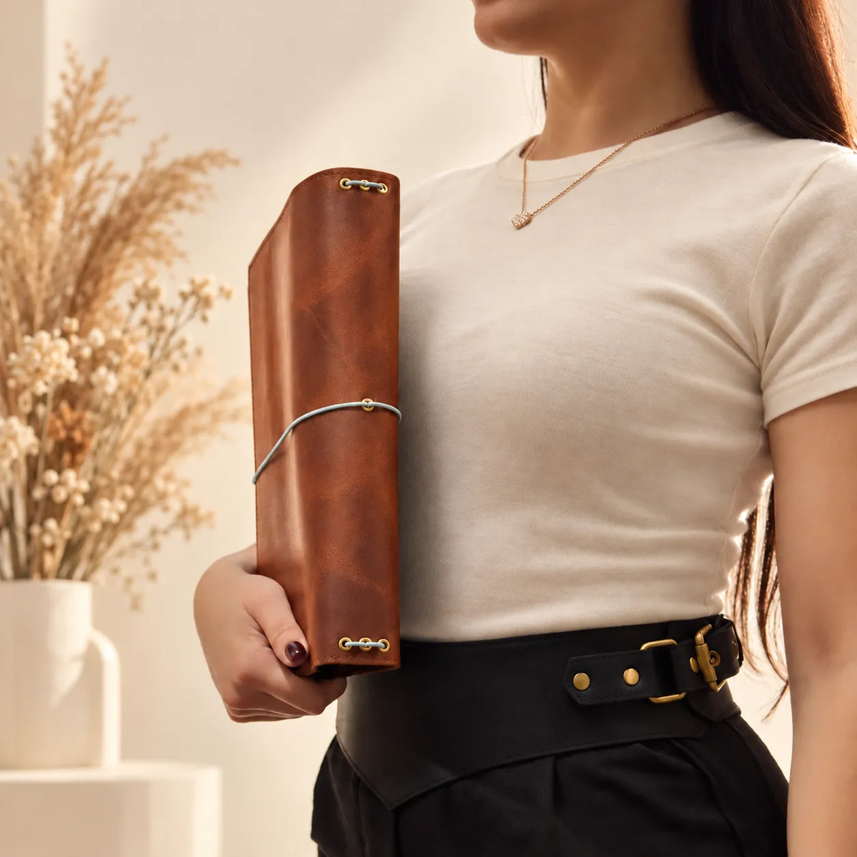 Young woman holding a handmade journal cover made from genuine leather with visible grain.