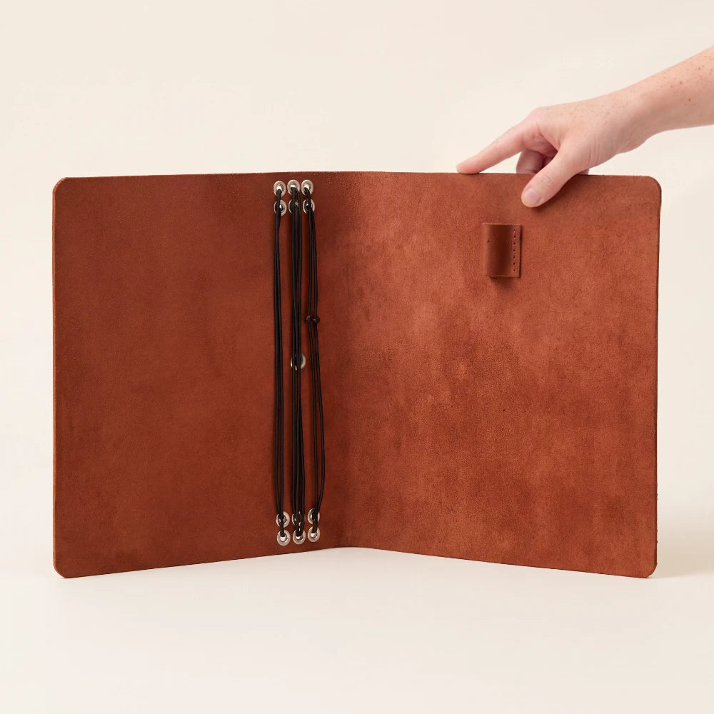 Reusable leather notebook wrap with six interior stretch retainers for paper refills.