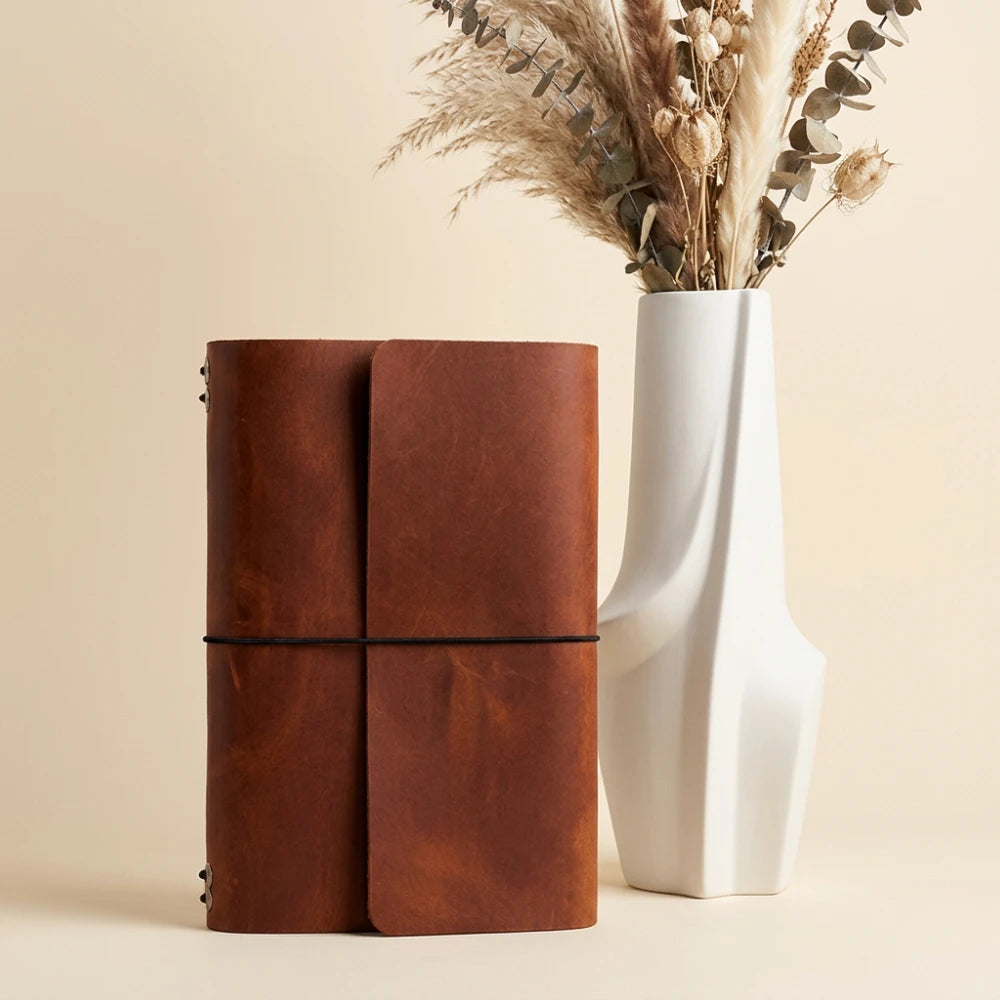 Refillable leather journal cover featuring six elastic bands and an integrated pen holder.