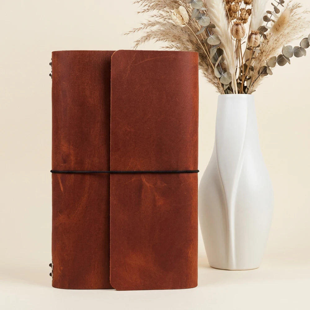 Soft leather refillable journal holder with six insert slots secured by elastic cords.