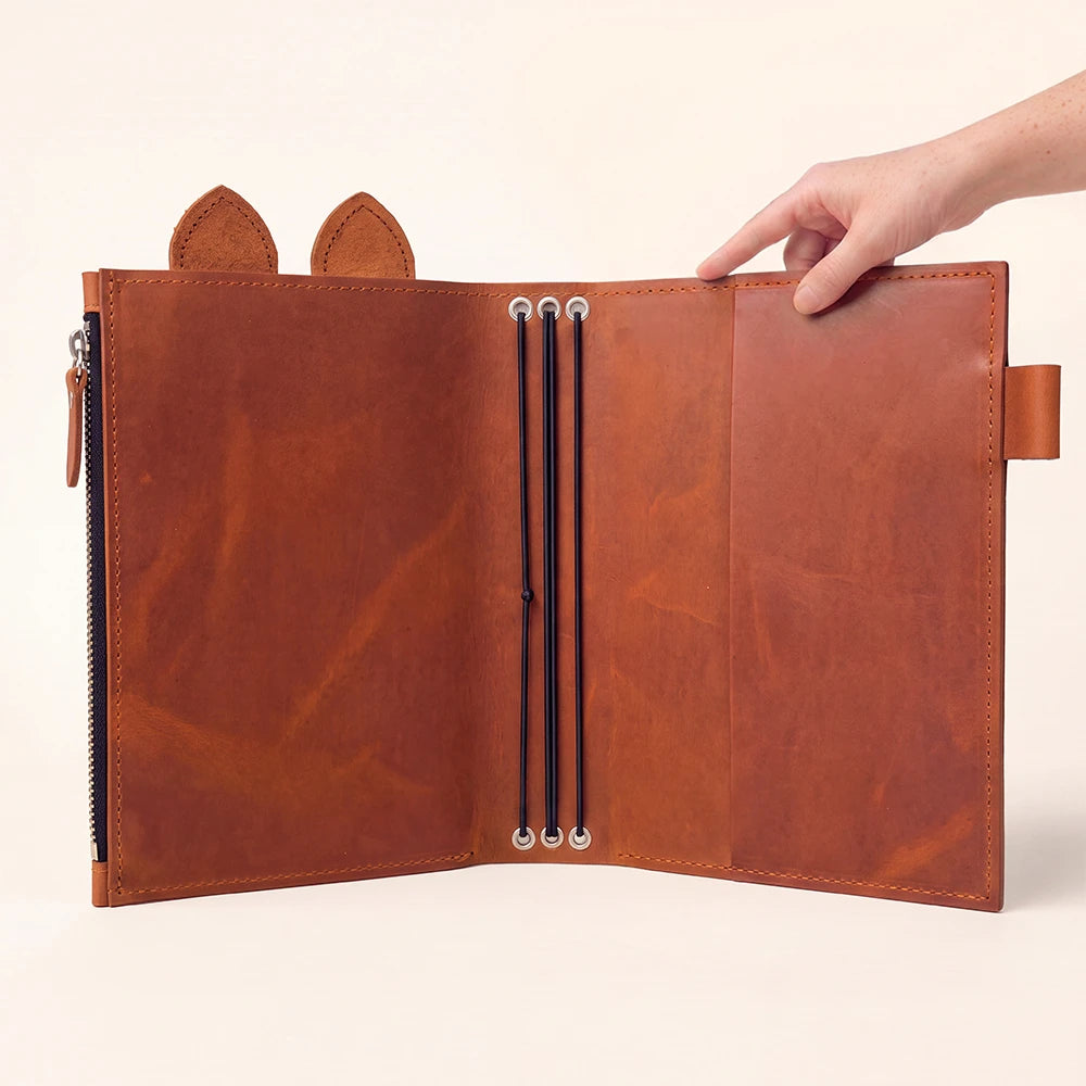 Leather notebook organizer with a large zipper pocket and carefully finished stitched edges.