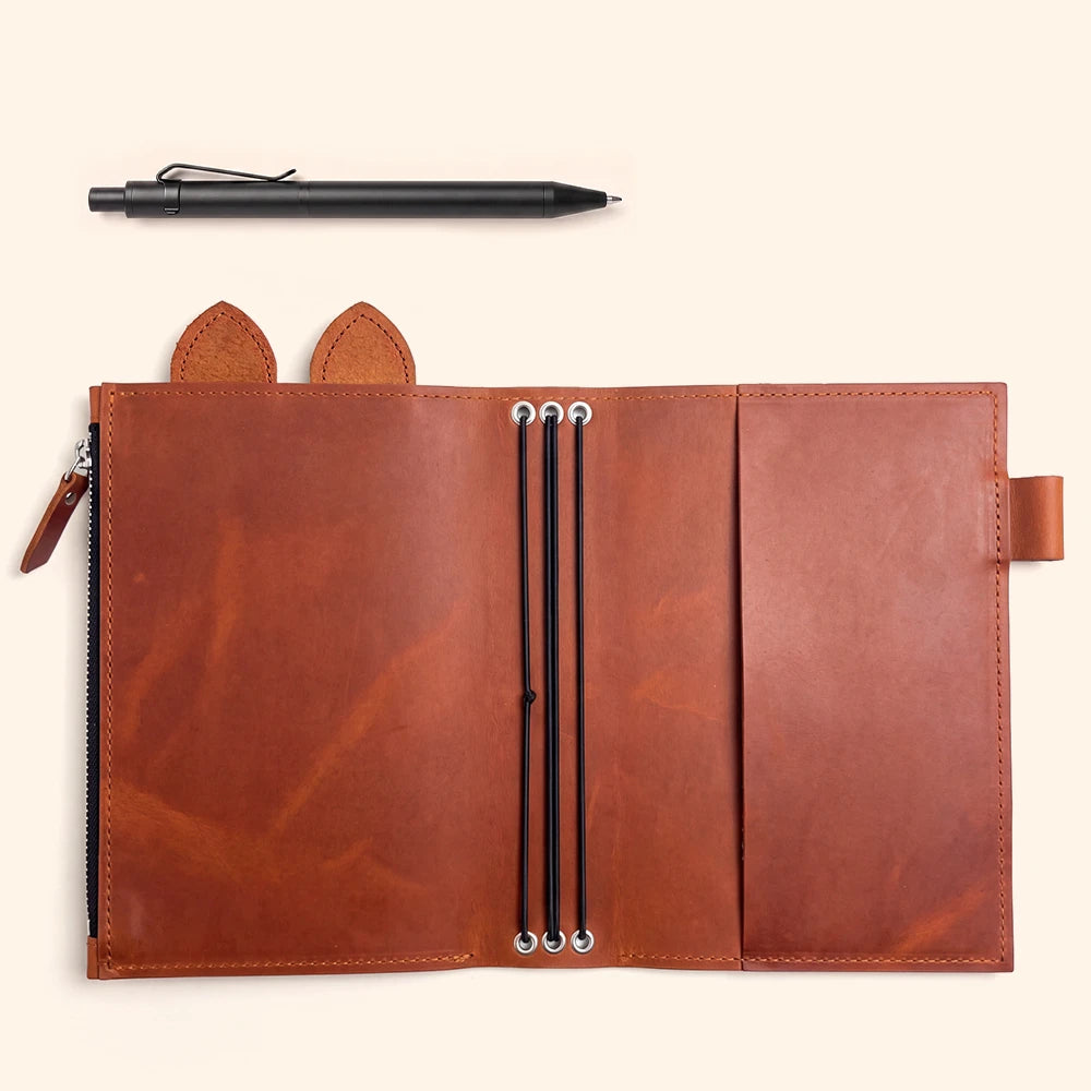 Brown leather journal cover opened to show its organized interior storage design.