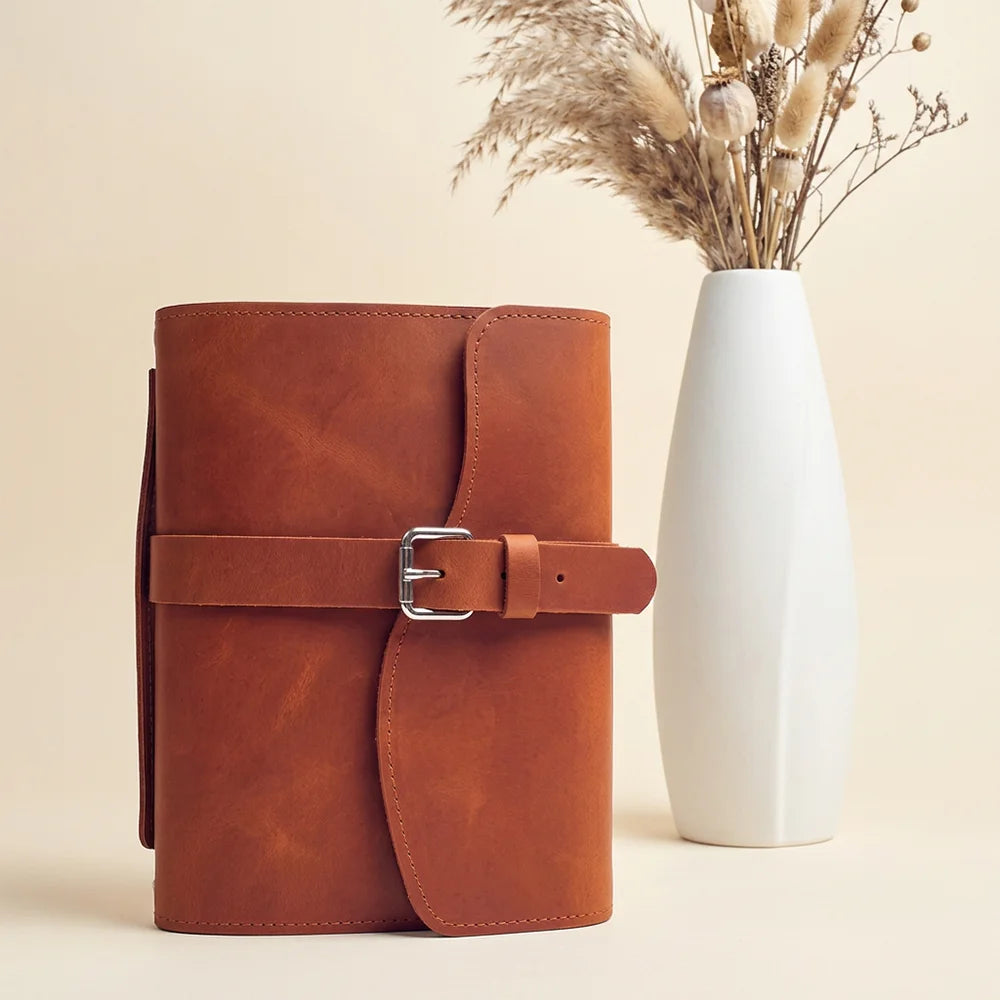 Full grain leather journal cover with storage compartments, pen loop, attached bookmark, and convenient carry grip.