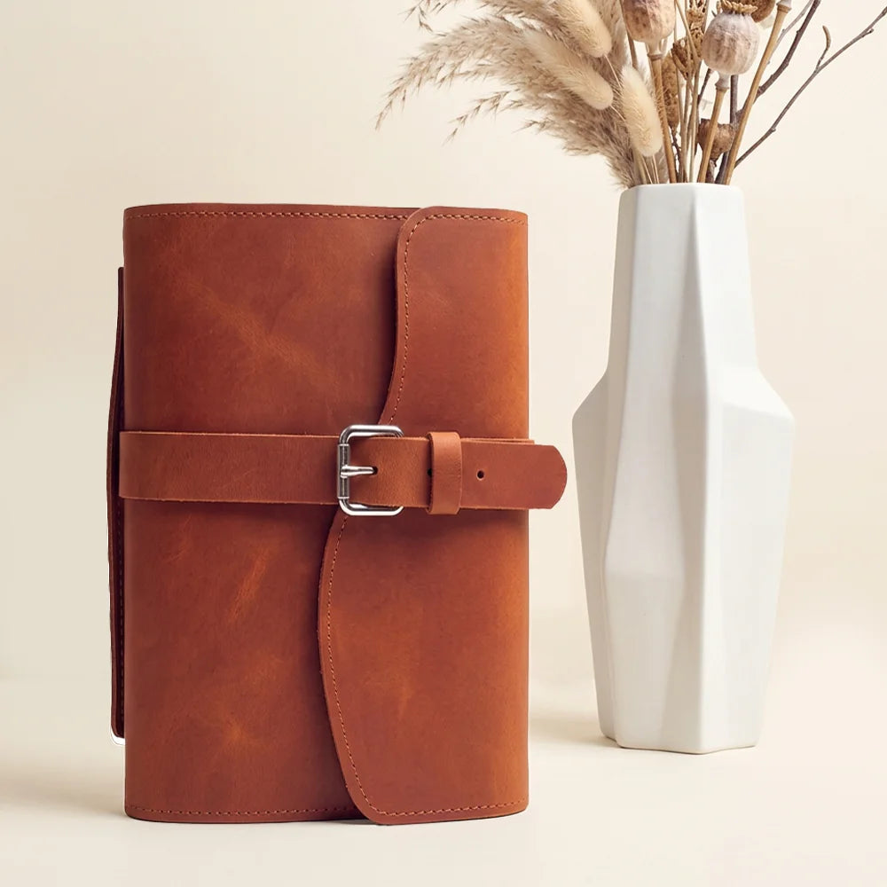 Handmade leather journal case featuring storage pockets, pen loop, page marker, and leather carry strap.
